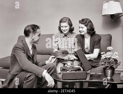 1930S 1940S GRUPPE VON TEENAGERN ZWEI MÄDCHEN EIN JUNGE SITZT ZUSAMMEN SPIELEN 78 RPM-PLATTEN AUF TRAGBAREN PHONOGRAPHEN - S8945 HAR001 HARS 1 JUGENDLICHER KOMMUNIKATIONSFREUND JUNGER ERWACHSENER NIMMT VINYL AUF JOY LIFESTYLE SOUND FRAUEN ZU HAUSE LEBEN KOPIEREN RAUM FREUNDSCHAFT HALBE LÄNGE DAMEN PERSONEN MÄNNER TEENAGER MÄDCHEN TEENAGER JUNGE UNTERHALTUNG TRAGBARE S & W PHONOGRAPH DATING GLÜCK FREIZEIT PLATTENSPIELER GESELLIGKEIT VERBINDUNG 78 RPM KONZEPTIONELL FREUNDLICH TEENAGER JUGENDLICHE ZWEISAMKEIT JUNGEN ERWACHSENEN MANN JUNGEN ERWACHSENEN FRAU SCHWARZ UND WEISS KAUKASISCHEN ETHNIZITÄT HAR001 ALTMODISCH Stockfoto