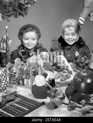 1940S 1950S LÄCHELNDES MÄDCHEN UND JUNGE SCHWESTER UND BRUDER SUCHEN IN SPIELZEUGLADEN-FENSTER GEFÜLLT MIT WEIHNACHTS-DISPLAY - X550 HAR001 HARS JUVENILE STRUMPF KRANZ ERFREUT FREUDE LIFESTYLE ZUFRIEDENHEIT FEIER FRAUEN BRÜDER STUDIO SCHUSS GESUNDHEIT KOPIEREN RAUM FREUNDSCHAFT GESCHÄFTE INSPIRATION MÄNNER GESCHWISTER SCHWESTERN WOLLEN B&W SHOPPER KÄUFER VERSUCHUNG TRÄUME GLÜCK KOPF UND SCHULTERN FRÖHLICH FRÖHLICHE AUFREGUNG GESCHWISTER LÄCHELT SPEICHERT DEZEMBER CONCEPTUAL DEZEMBER 25 FRÖHLICHER WUNSCH KOMMERZ WACHSTUM FREUDIG JUGENDLICHE SCHWARZ UND WEISSE UNTERNEHMEN KAUKASISCHEN ETHNIZITÄT HAR001 ALTMODISCHE WÜNSCHE Stockfoto