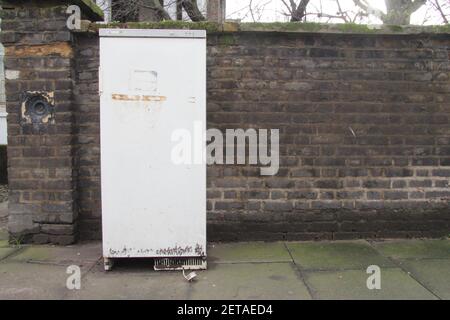 Verlassene Kühlschrank gegen Backsteinmauer auf dem Bürgersteig in London Stockfoto