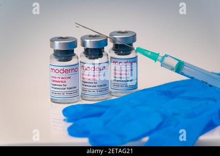 LONDON, ENGLAND - 28. FEBRUAR 2021: Glasfläschchen, die Dosen des Moderna COVID Coronavirus-Impfstoffs mit einer Spritzeninjektion und einem Tröpfchen bei t enthalten Stockfoto