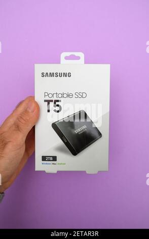 Paris, Frankreich - 8. Oktober 2018: POV männliche Hand hält neues Paket mit Samsung T5 Portable SSD mit 2TB Terabyte Kapazität - isoliert auf violettem Hintergrund Stockfoto