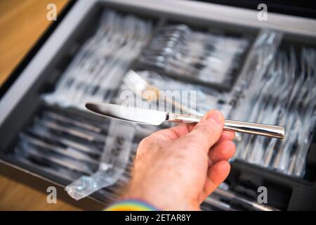 POV männliche Hand hält neue Besteck-Sets Besteck Inspektion der Essmesser Stockfoto