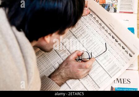 Paris, Frankreich - 13. Feb 2021: POV männliche Hand liest FT Weekend Financial Times schaut sorgfältig auf die Marktdaten verschiedener börsennotiger Unternehmen Grafiken - mit einer Brille Stockfoto