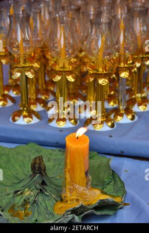 Buddha Tag in Bangkok, Thailand - Visakha Bucha Tag im Thai Tempel - brennende große gelbe Kerze mit vielen Kerzen in den goldenen Kerzenhaltern angezündet. Stockfoto