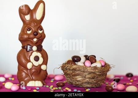 Schokoladenhase und Vogelnest voller ostermandeleier Vor weißem Hintergrund Stockfoto