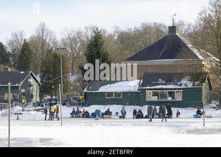 ZUTPHEN, NIEDERLANDE - 14. Feb 2021: Bau einer Eisbahn mit Menschen in der Schneelandschaft Vorbereitung auf Eislaufen Stockfoto