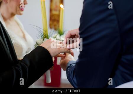 Ein flacher Fokus des Bräutigams, der einen Ring aufsetzt Der Finger der Braut während der Trauung Stockfoto