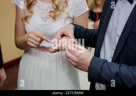 Ein flacher Fokus des Bräutigams, der einen Ring aufsetzt Der Finger der Braut während der Trauung Stockfoto