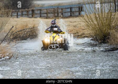 Der Mann auf dem ATV kreuzt einen Stream. Touristischen Spaziergänge auf einem cross-country Gelände. Stockfoto