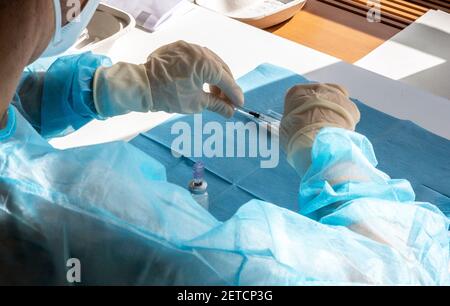 Medizinisches Personal bereitet während eines massiven Impftages in einem Gesundheitszentrum eine Injektion des Impfstoffs vor. Spritzen in Vorbereitung und gebrauchsfertig. Stockfoto