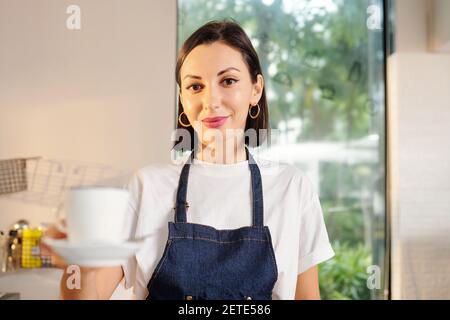 Kellnerin bietet eine Tasse Kaffee an Stockfoto