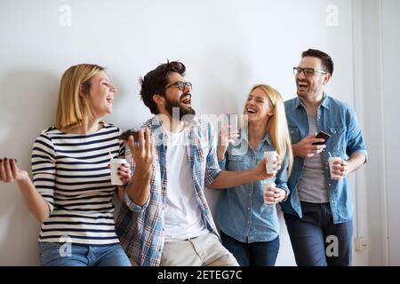 Eine Gruppe junger Freunde lacht während ihrer Kaffeepause heftig. Stockfoto