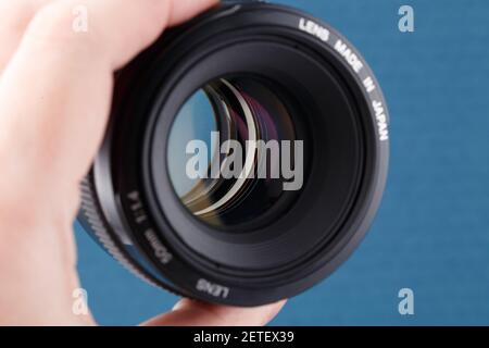 Modernes digitales 50-mm-dslr-Objektiv mit Handgriff auf blauem Hintergrund – Nahaufnahme mit selektivem Fokus. Stockfoto