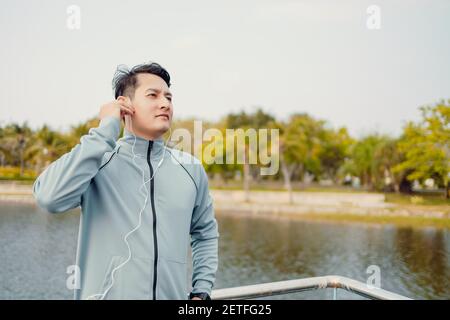 Junger Sportmann joggt und hört Musik im Park. Stockfoto