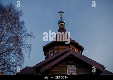 Giebel Dach der hölzernen orthodoxen Kirche mit Blockmauern, sechsseitigen Turm, blaue Kuppel und vergoldeten orthodoxen Kreuz mit einer Ikone über dem Eingang auf der Rückseite Stockfoto