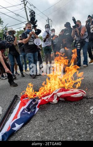 Stone Mountain, GA, USA. August 2020, 15th. Demonstranten verbrennen eine amerikanische Flagge und eine Flagge der Konföderierten während einer Kundgebung zum Schutz des Steinbergs. Mehrere rechte Milizgruppen und Gegenprotestierer sollten am Samstag in Stone Mountain, GA, zusammenkommen. Stockfoto