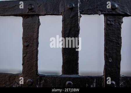 Schwarz lackierter Metallzaun. Metallstäbe miteinander verschweißt. Metallgeländer in schwarz auf der Straße. Dunkler Rasterhintergrund. Struktur der Hardware-Tuch Heftklammern. So Stockfoto