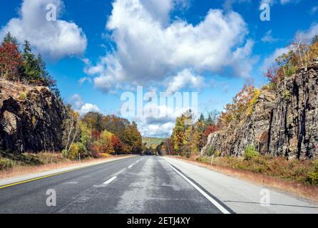 Faszinierende bunte verwinkelte Vermont Highway Straße gesäumt von Herbst Ahorn Bäume auf Felsen und Klippen lädt Reisende auf eine unvergessliche Reise auf Stockfoto