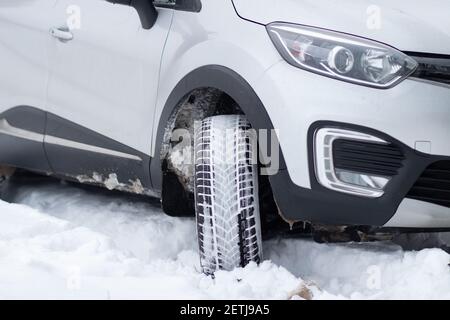 Ein Fragment der Front eines SUV mit Scheinwerfern, Frontstoßstange, Nebelscheinwerfer auf einer Winterstraße. Winterliche Fahrbedingungen auf einer verschneiten Straße Stockfoto