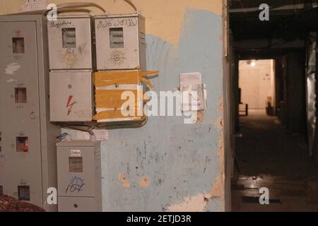 Alte Stromzähler an der zertrümmerten Wand im Foyer des alten sowjetischen Massenwohnungsgebäudes in Tiflis, Georgien Stockfoto