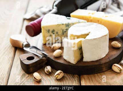 Verschiedene Käsesorten, Trauben, Wein und Snacks auf einem alten Holzhintergrund Stockfoto