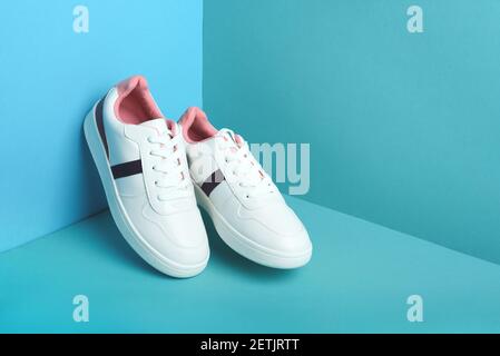 Blaue Sport Sneakers Schuhe auf dem blauen Hintergrund. Fitness-Hintergrund. Gesundes Lifestyle-Konzept. Trendige Vorderansicht. Stockfoto