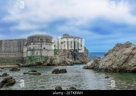 Blick auf die Festungsmauern, felsige Küste und blaues Meer in Dubrovnik, Kroatien. Atemberaubende Aussicht auf die Stadtmauern von Dubrovnik und die Altstadt von Dubrovnik. Stockfoto