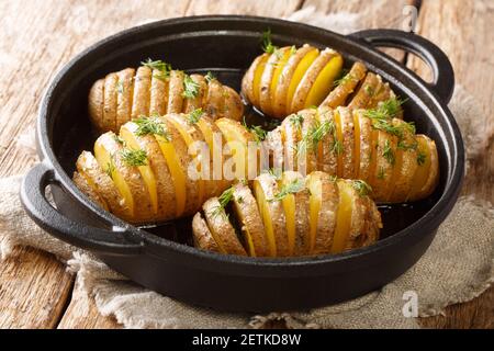 Rustikal geschnittene und gebackene Hasselback-Kartoffeln aus der Nähe auf einer Pfanne auf dem Tisch. Horizontal Stockfoto