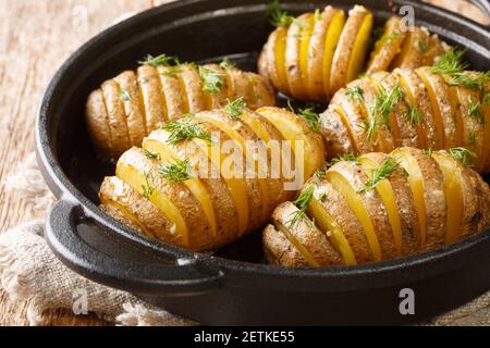 In einer Pfanne auf dem Tisch werden von Schweden gebackene Hasselback-Kartoffeln aus nächster Nähe gebacken. Horizontal Stockfoto