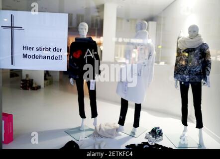 Köln, Deutschland. März 2021, 02nd. Ein Plakat mit der Aufschrift 'Hier stirbt der Modehandel' und ein schwarzes Kreuz hängt im Schaufenster eines Ladens. Quelle: Oliver Berg/dpa/Alamy Live News Stockfoto