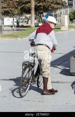 Elegant gekleideter älterer Mann, der Fahrrad fährt. Stockfoto