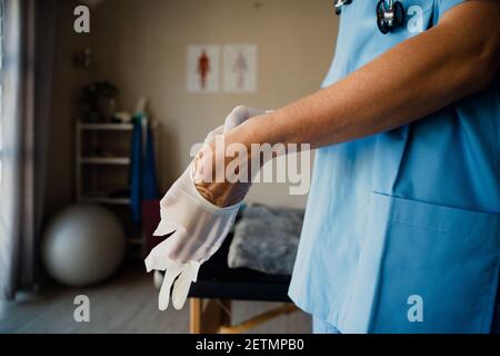 Nahaufnahme der kaukasischen Krankenschwester, die sich auf die Konsultation vorbereitet Handschuhe, die sich auf den Termin mit kranken Patienten vorbereiten Stockfoto