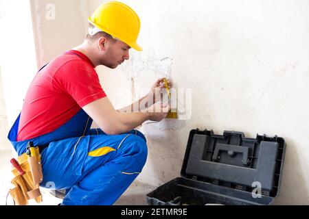 Elektriker, der den Spannungspegel in den Steckerkabeln überprüft Stockfoto