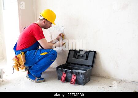 Elektriker, der den Spannungspegel in den Steckerkabeln überprüft Stockfoto