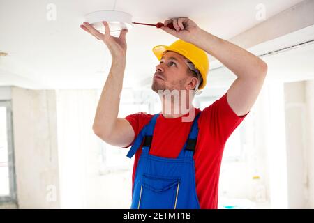 Befestigung der Deckenleuchte mit einem Schraubendreher, der sichergeht, dass sie befestigt bleibt Mit Stabilität Stockfoto
