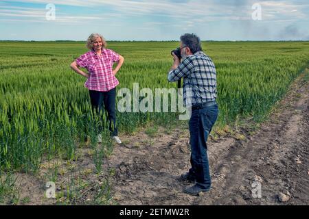 Der Fotograf fotografiert sein Modell im jungen Weizen. Stockfoto