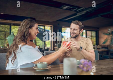 Lächelnder Mann mit Geschenk und enthusiastische Frau Stockfoto