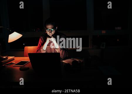 Kaukasischen männlichen müde Freiberufler auf Handgelenke Lektüre Artikel auf Laptop am Schreibtisch des Heimbüros Stockfoto