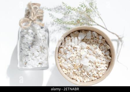 Pappbecher mit Haferflocken und Meersalz. Schrubben Sie die Haut. Spa-Produkte zur Reinigung der Haut und für ein entspannendes Bad im Glasgefäß mit Korkstopfen Stockfoto