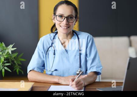 Ärztin mit Brille, die Krankengeschichte ausfüllt Stockfoto