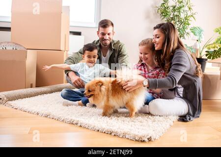 Vierköpfige Familie mit ihrem Hund auf dem Teppich Der neuen Wohnung Spaß haben Stockfoto