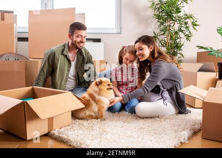 Mama, Papa, ihre Tochter und ihr Hund ziehen ein, Familienkonzept Stockfoto