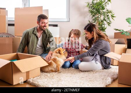 Mama, Papa, ihre Tochter und ihr Hund ziehen ein, Familienkonzept Stockfoto
