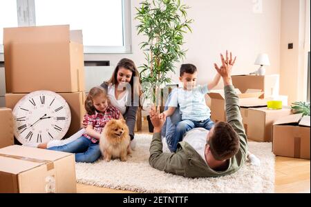 Mama, Papa, ihre Kinder und ihr Hund ziehen in die neue Wohnung und haben Spaß dabei Stockfoto