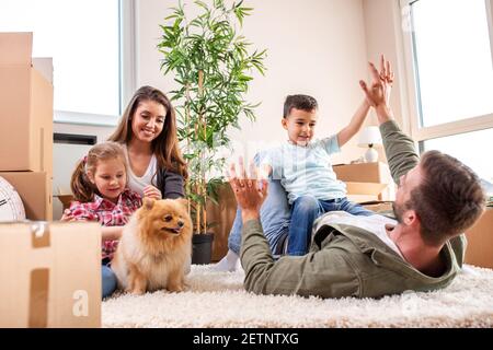 Mama, Papa, ihre Kinder und ihr Hund ziehen in die neue Wohnung und haben Spaß dabei Stockfoto