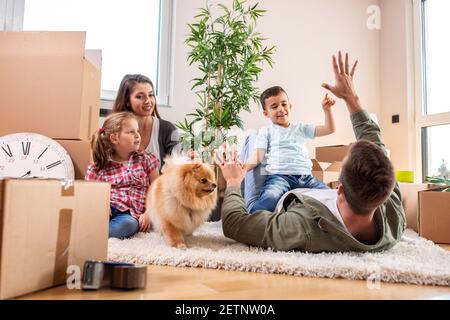 Mama, Papa, ihre Kinder und ihr Hund ziehen in die neue Wohnung und haben Spaß dabei Stockfoto