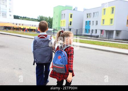 Kinder mit Aktentaschen über den Schultern auf dem Hintergrund der Schule. Stockfoto