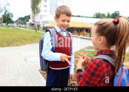 Kinder mit Aktentaschen über den Schultern auf dem Hintergrund der Schule. Stockfoto