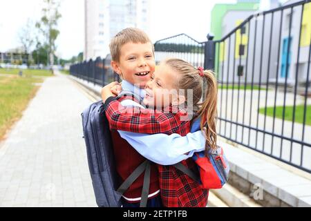 Kinder mit Aktentaschen über den Schultern auf dem Hintergrund der Schule. Stockfoto