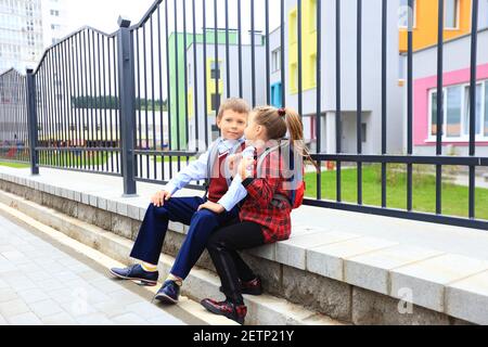 Kinder mit Aktentaschen über den Schultern auf dem Hintergrund der Schule. Stockfoto